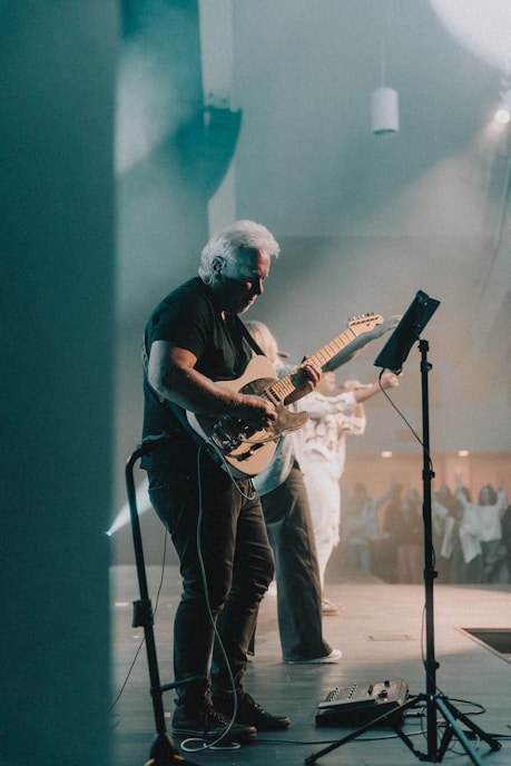 a man playing a guitar in front of a microphone