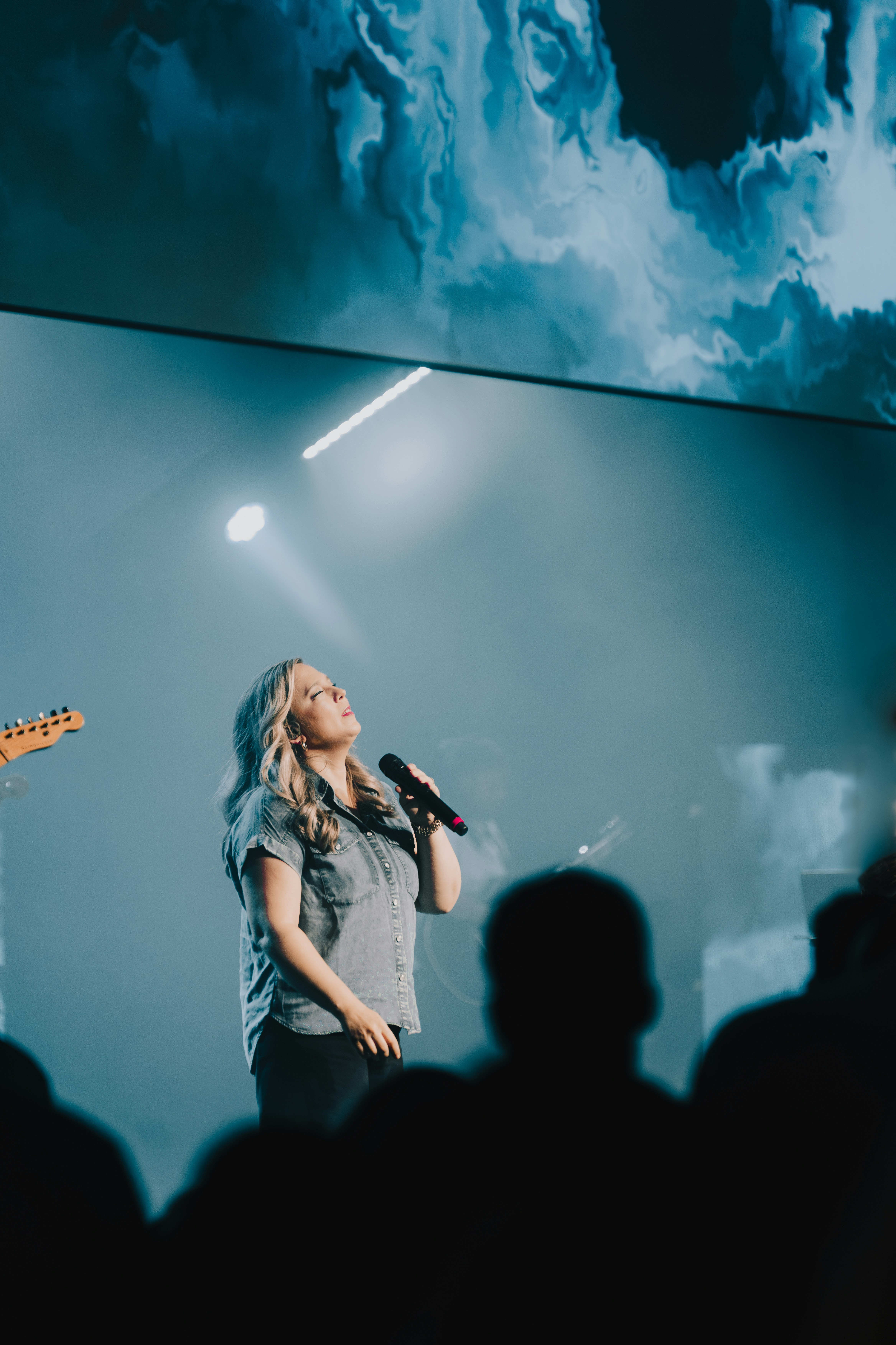 a woman singing into a microphone in front of a crowd