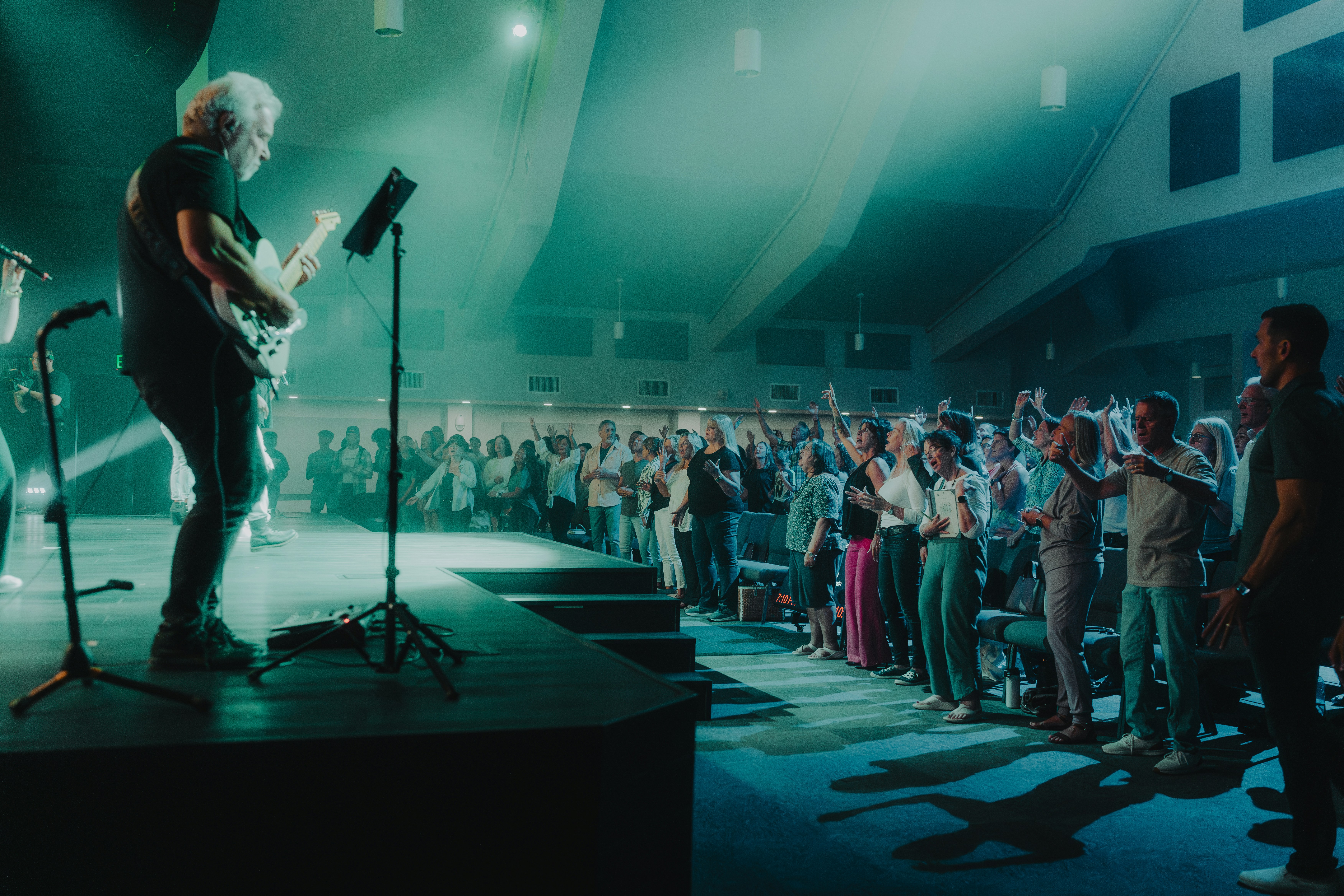 a man standing on a stage with a guitar in front of a crowd of people