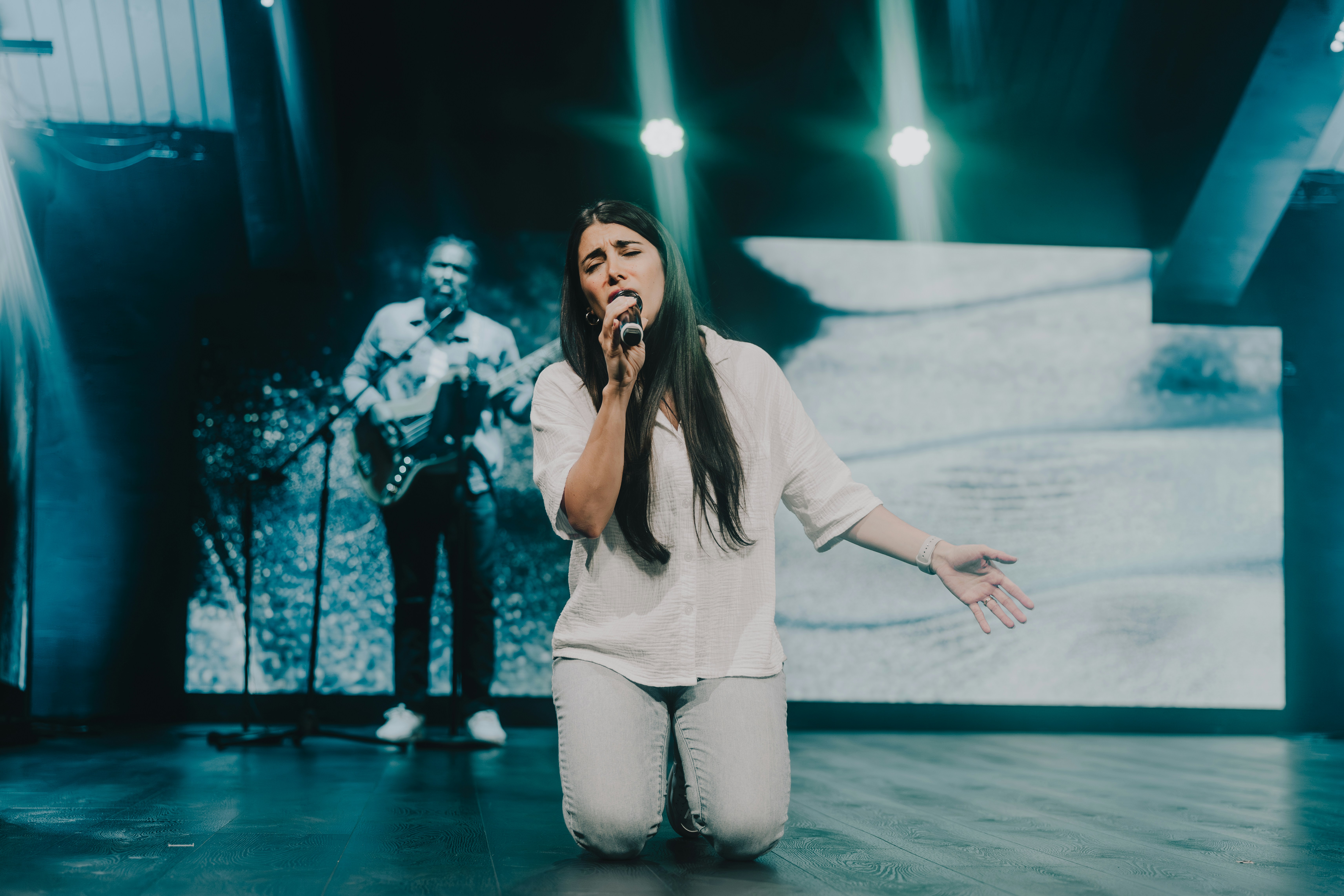 a woman sitting on the floor while holding a microphone