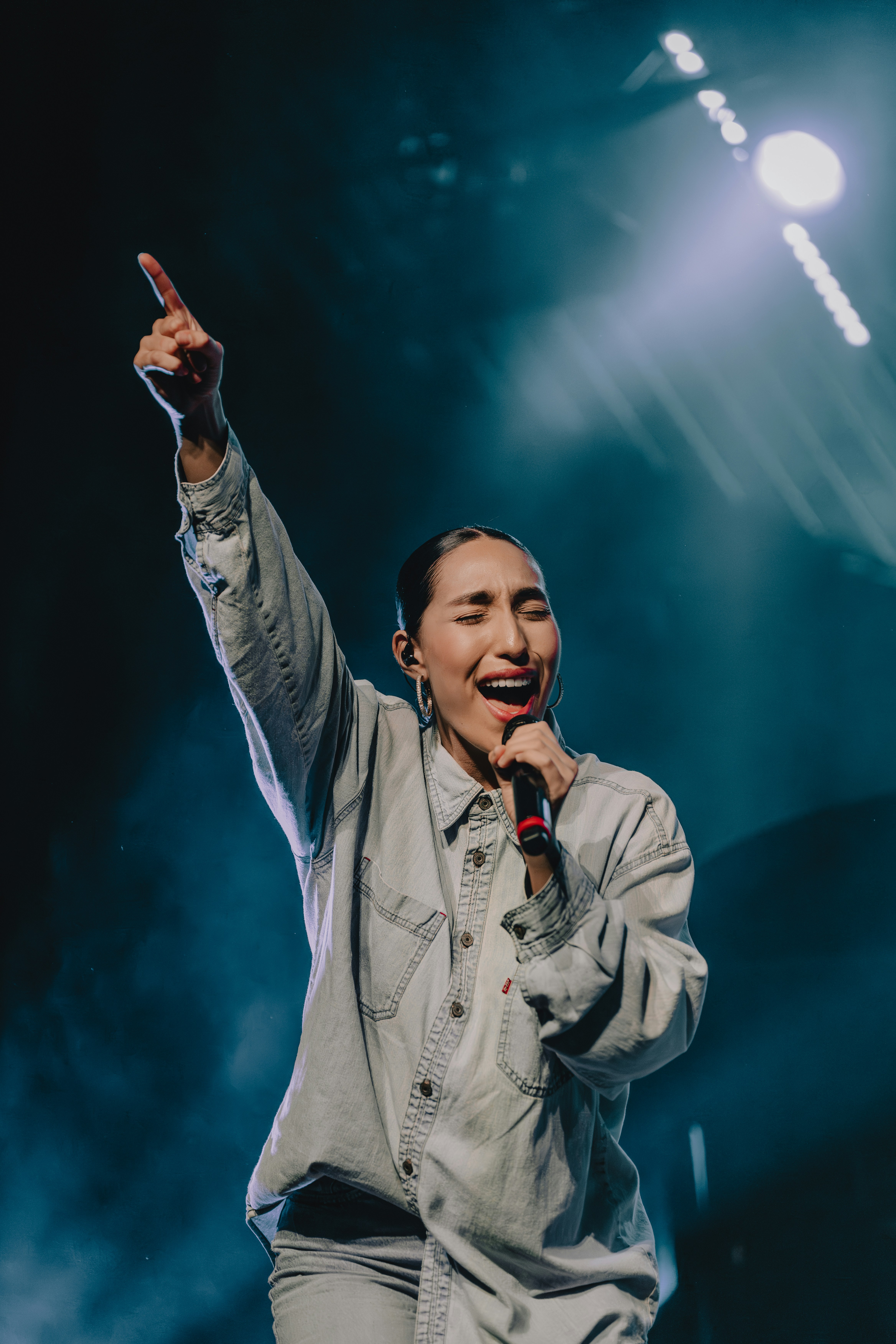 a woman singing into a microphone on stage
