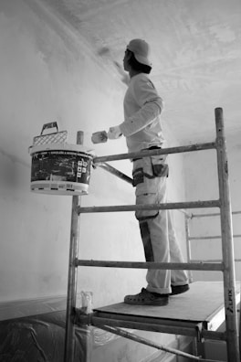 a man painting a wall with a paint roller