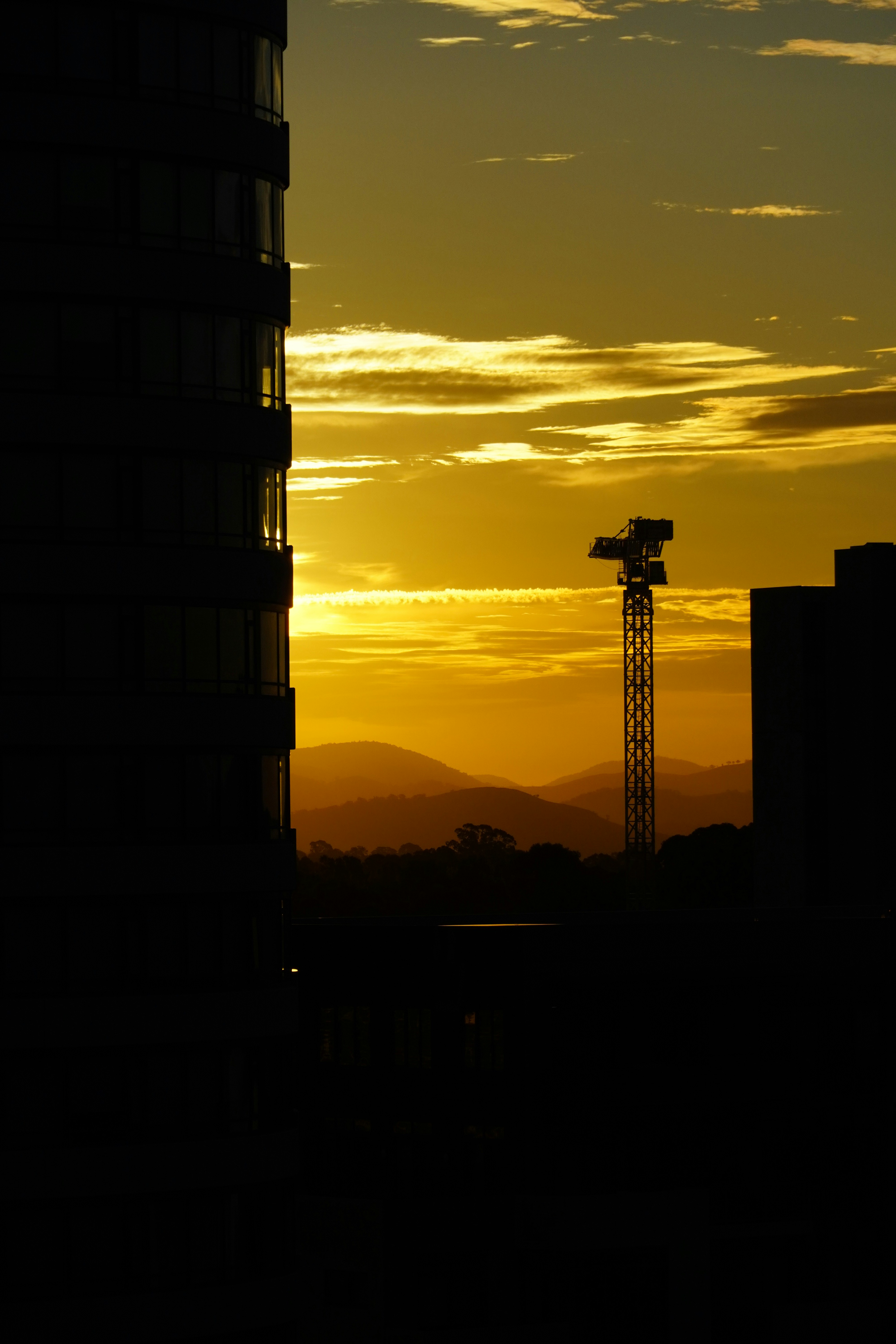 o sol está se pondo atrás de um prédio alto