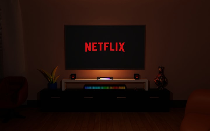 A dark room illuminated by the glow of a TV screen displaying a streaming service