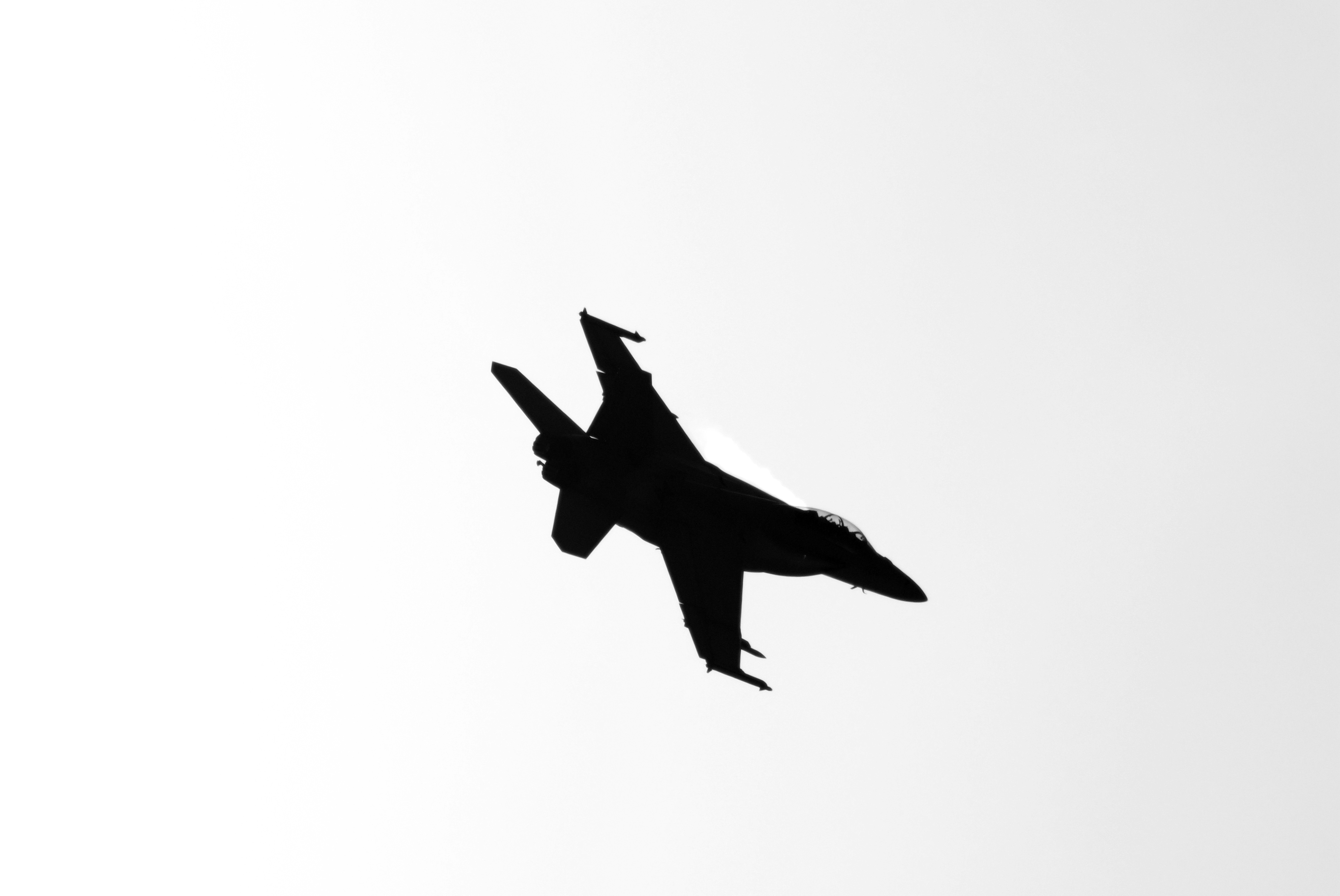 a fighter jet flying through a white sky