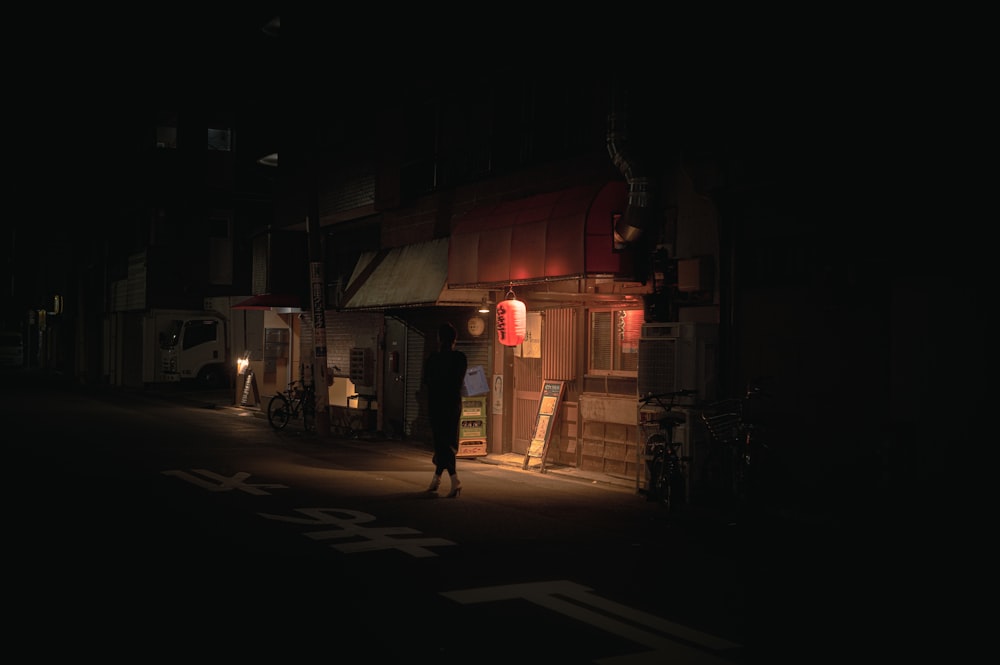 a dark street at night with a person standing in the doorway