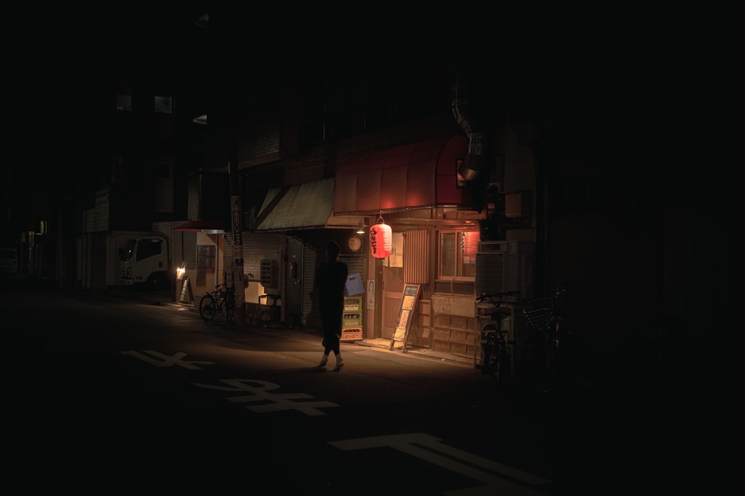 a dark street at night with a person standing in the doorway,