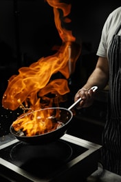 a person cooking on a stove with flames