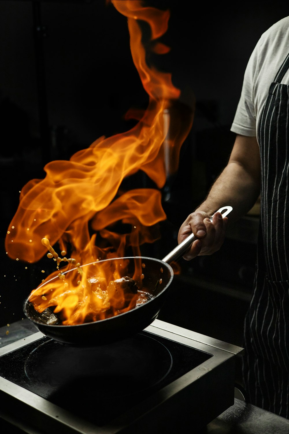 a person cooking on a stove with flames