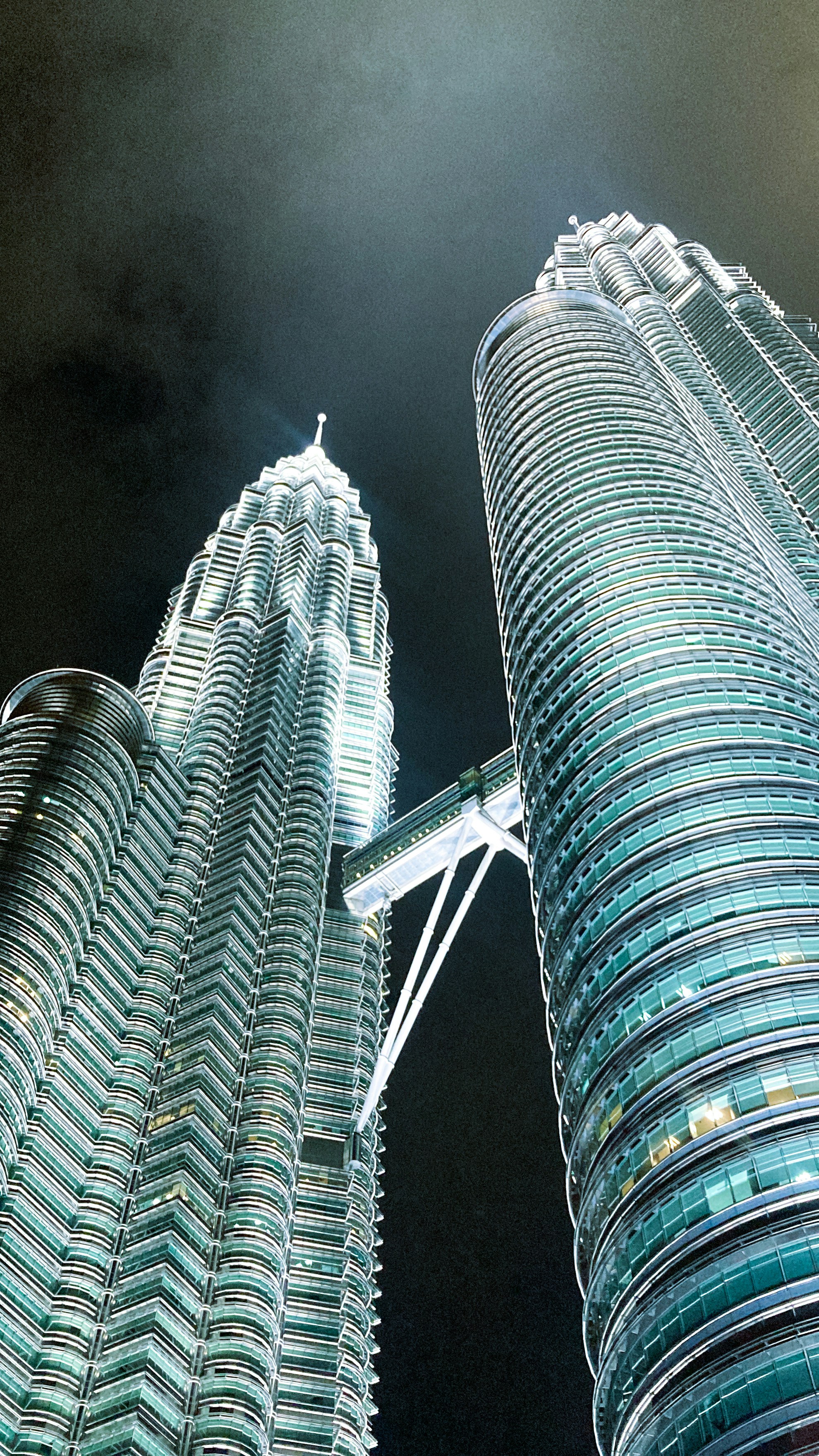 Petronas Twin Towers Kuala Lumpur at night with dark sky and glowing city lights below