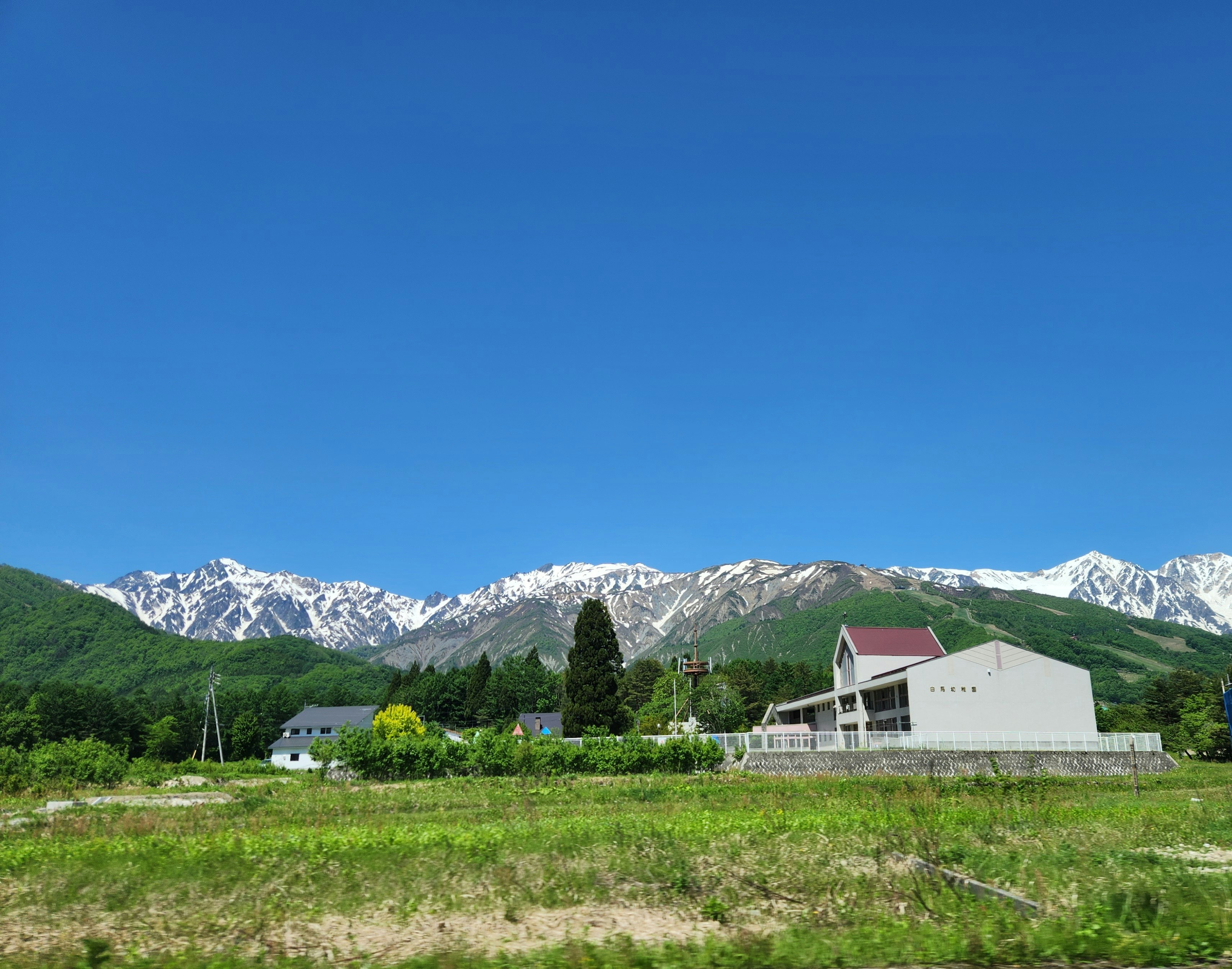 a house in the middle of a field with mountains in the background