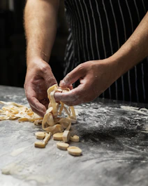 a man is making pasta on a table