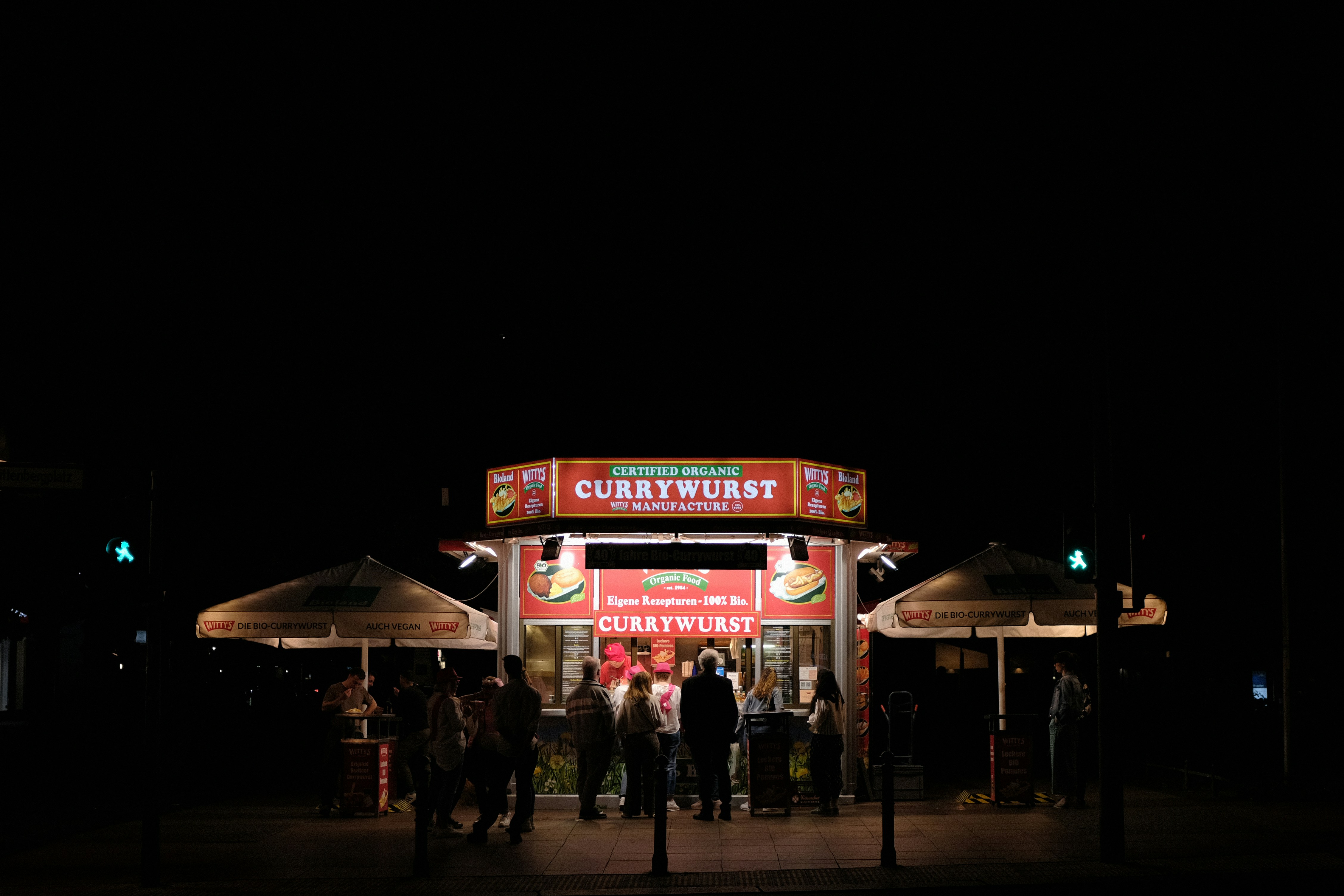 a group of people standing outside of a food stand