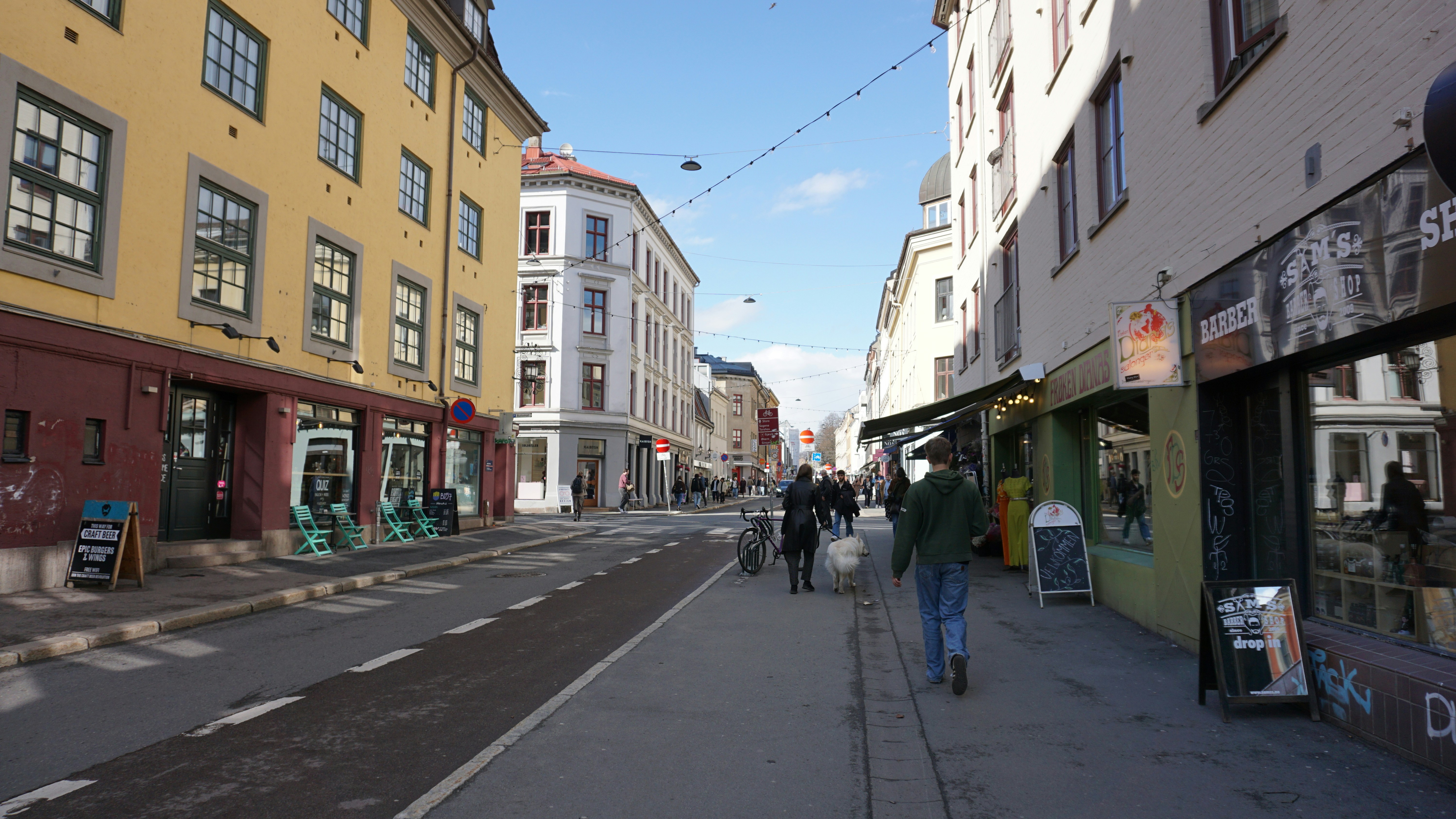 a man walking down a street next to tall buildings