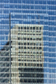 a building is reflected in the glass windows of another building