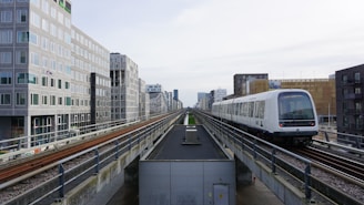 a train traveling down train tracks next to tall buildings