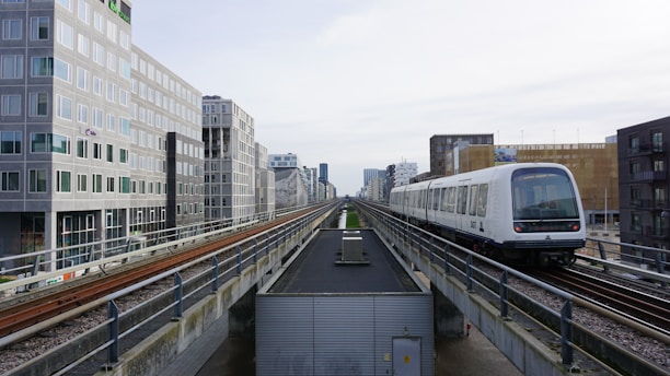 a train traveling down train tracks next to tall buildings