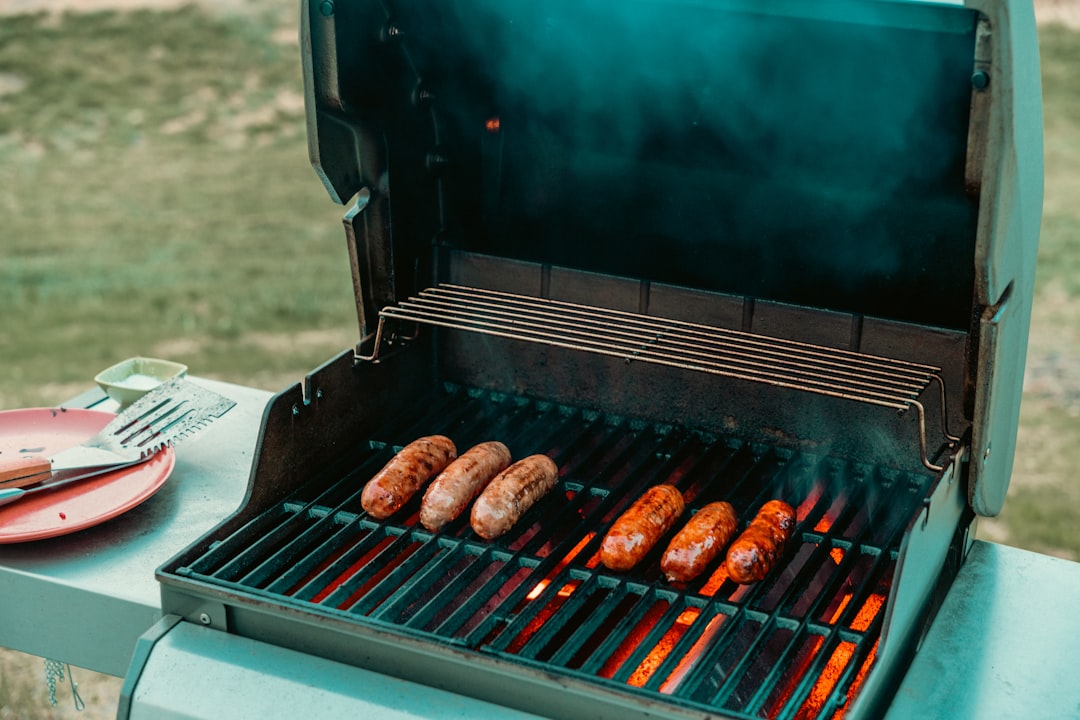a grill with hot dogs and sausages cooking on it,