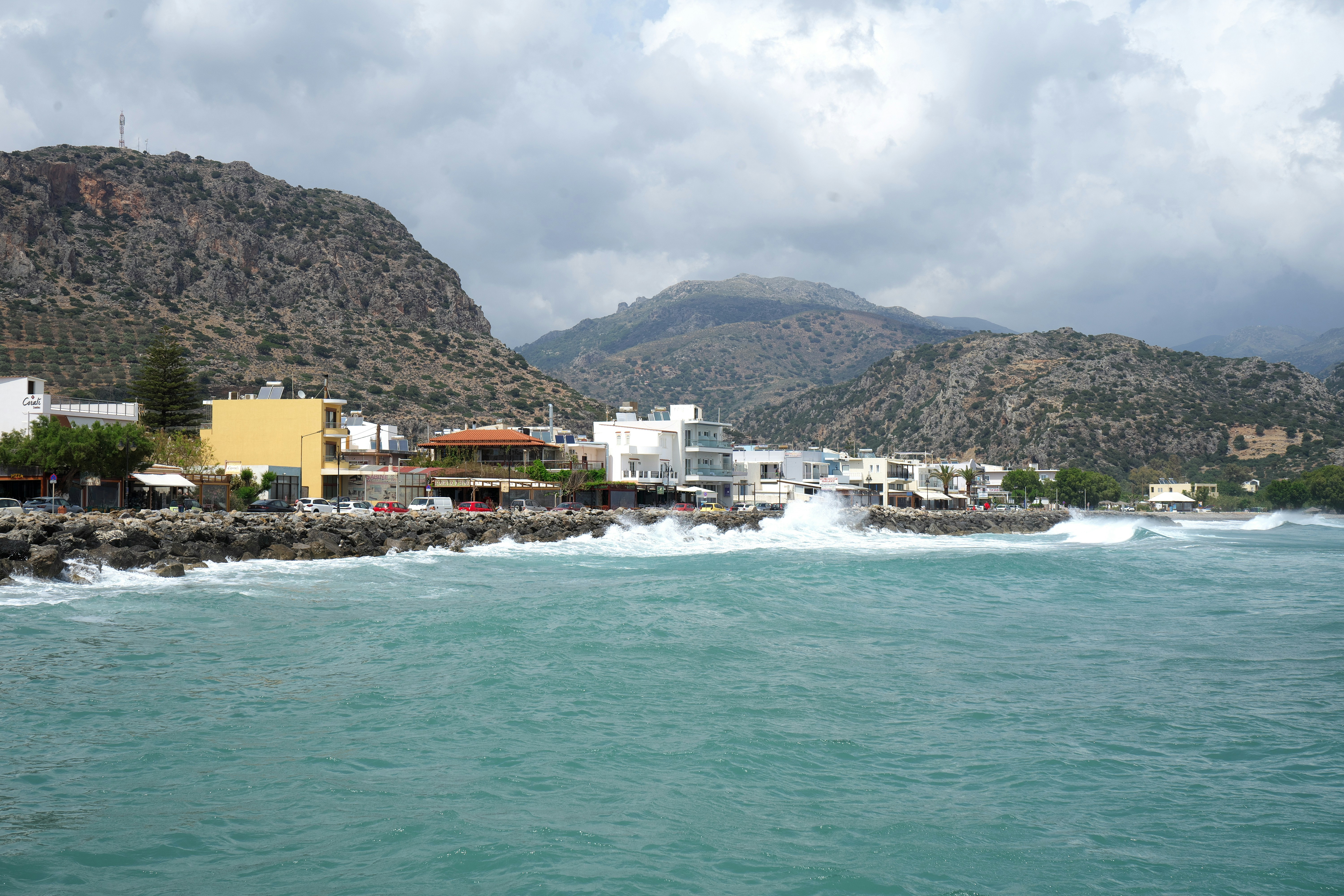 a body of water with a mountain in the background, Waves crashing into stones... Paleochora, Crete, Greece