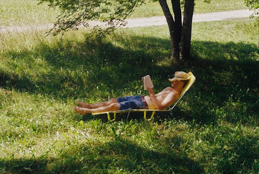 a man laying in a lawn chair under a tree