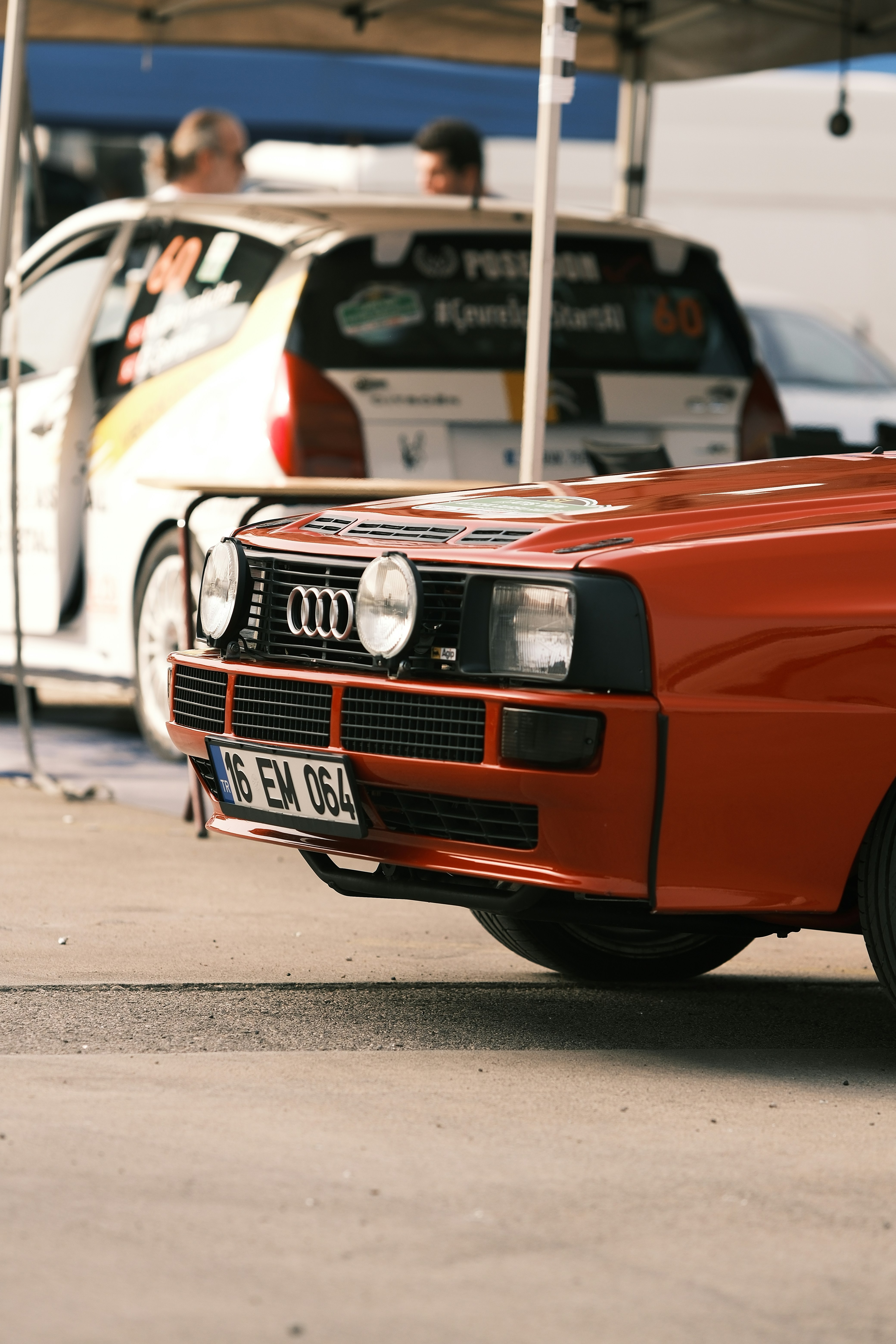 an orange car parked in front of a white car