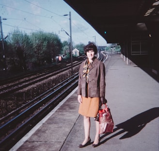 a woman standing on a train platform holding a bag