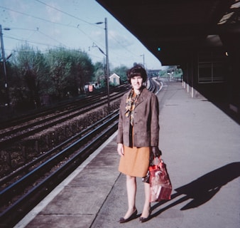 a woman standing on a train platform holding a bag
