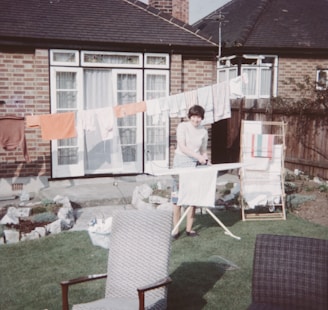 a woman standing in front of a house next to a lawn
