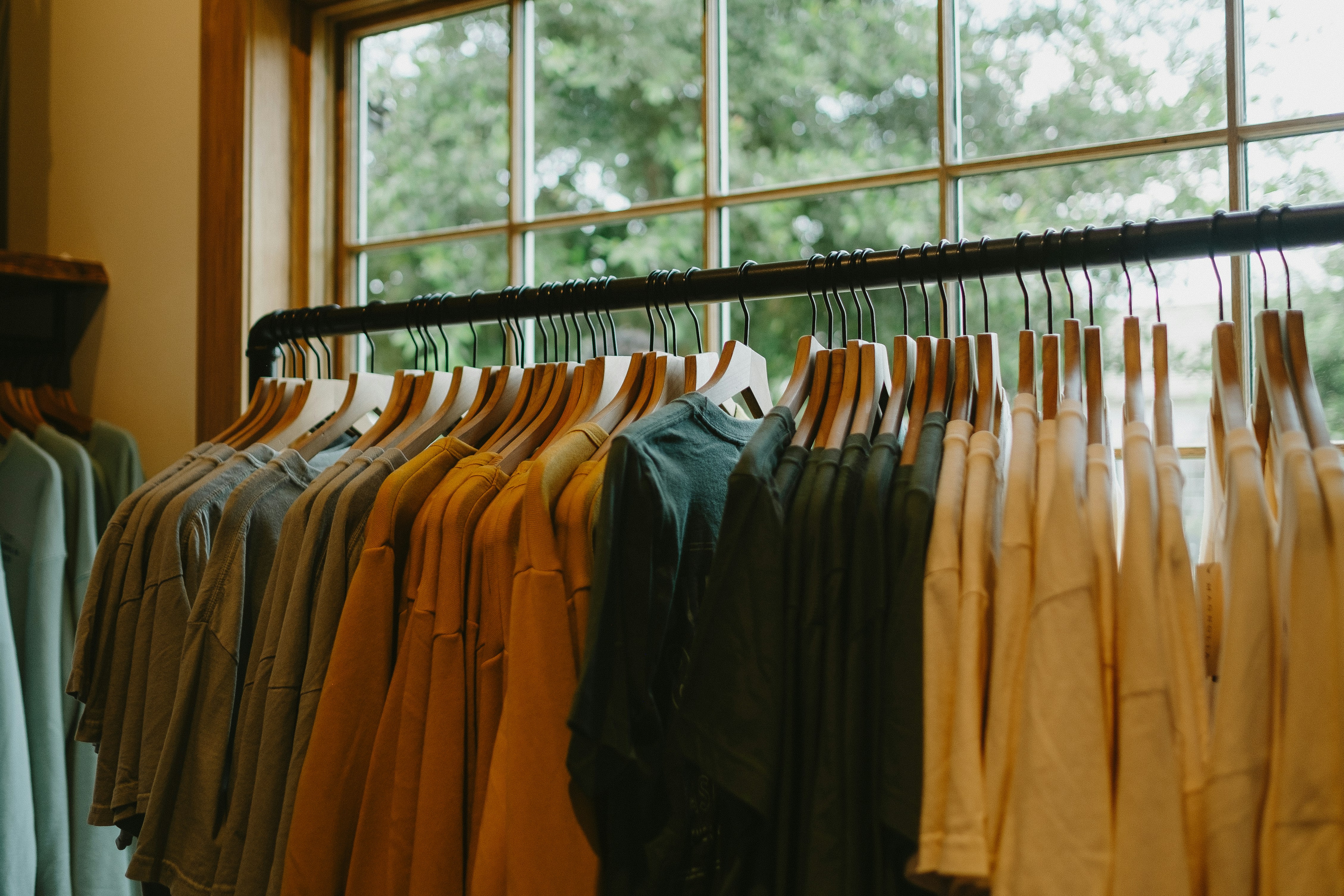 a rack of shirts hanging in front of a window