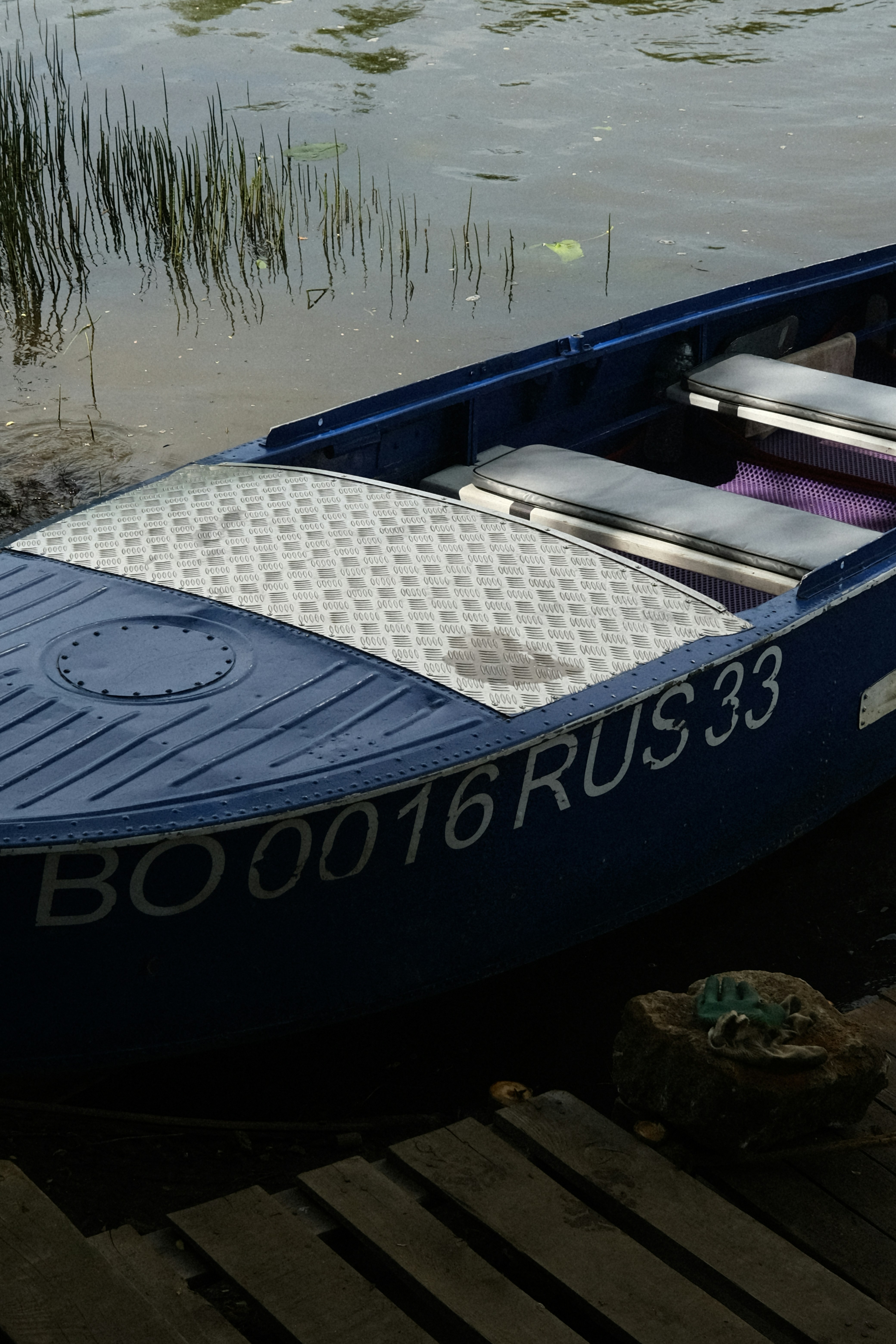 perahu biru duduk di atas dermaga kayu