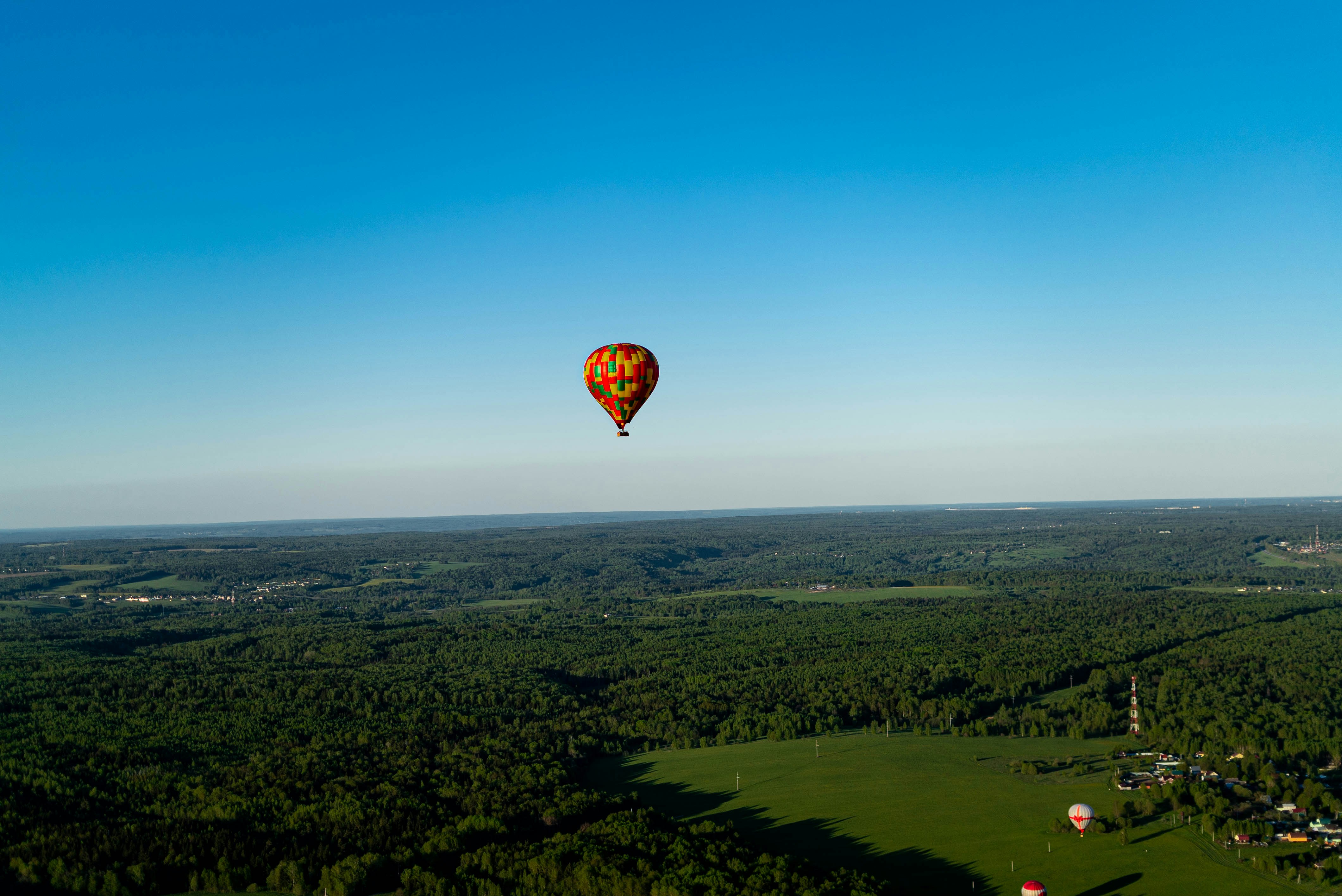A hot air balloon flying over a lush green field photo – Free Forest ...