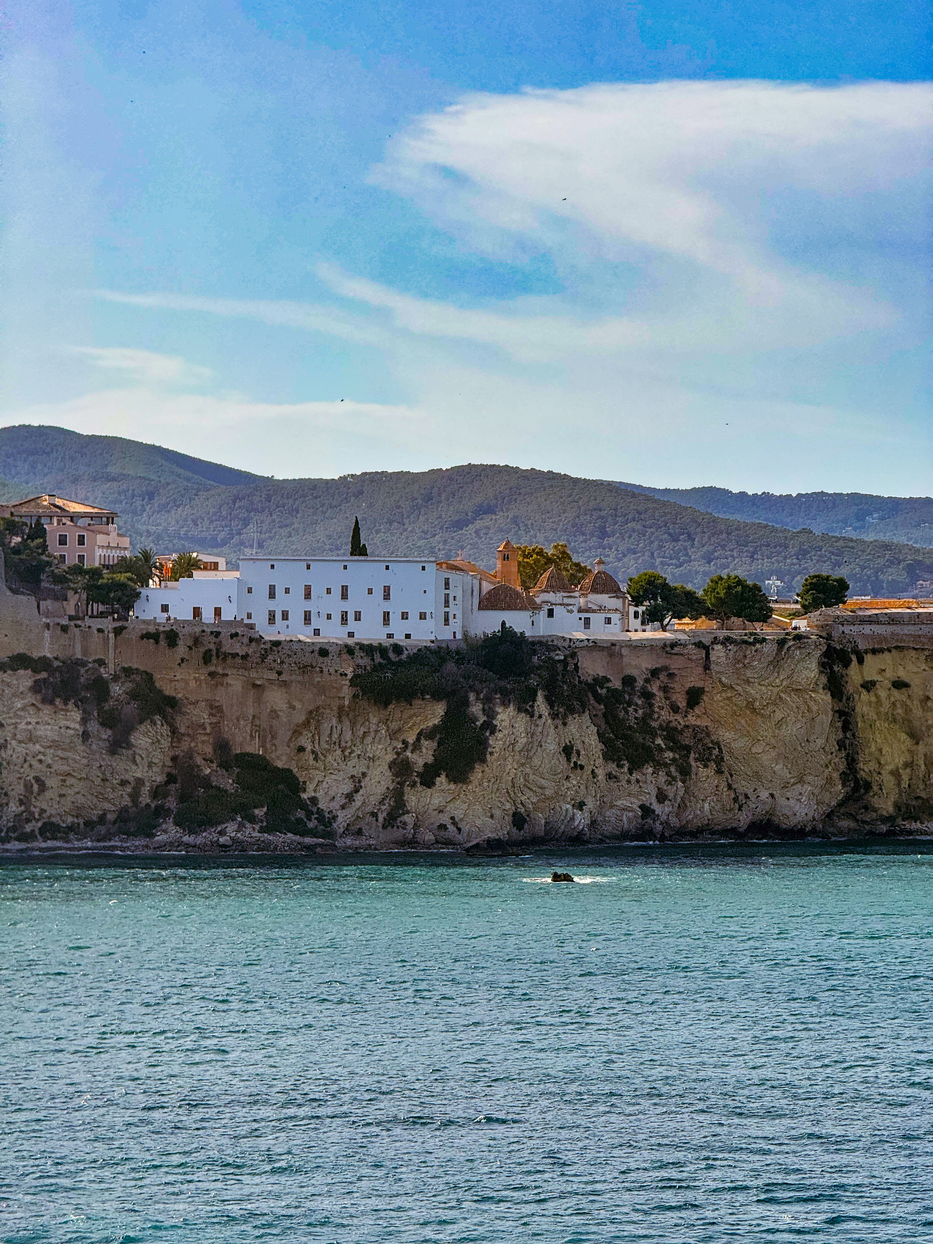 a white building sitting on top of a cliff next to a body of water