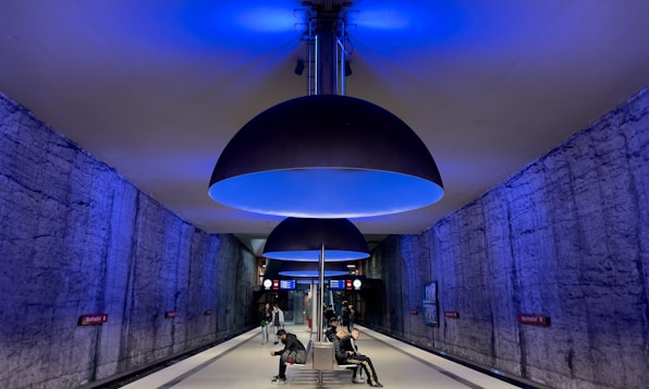 a couple of people sitting on a bench under a blue light