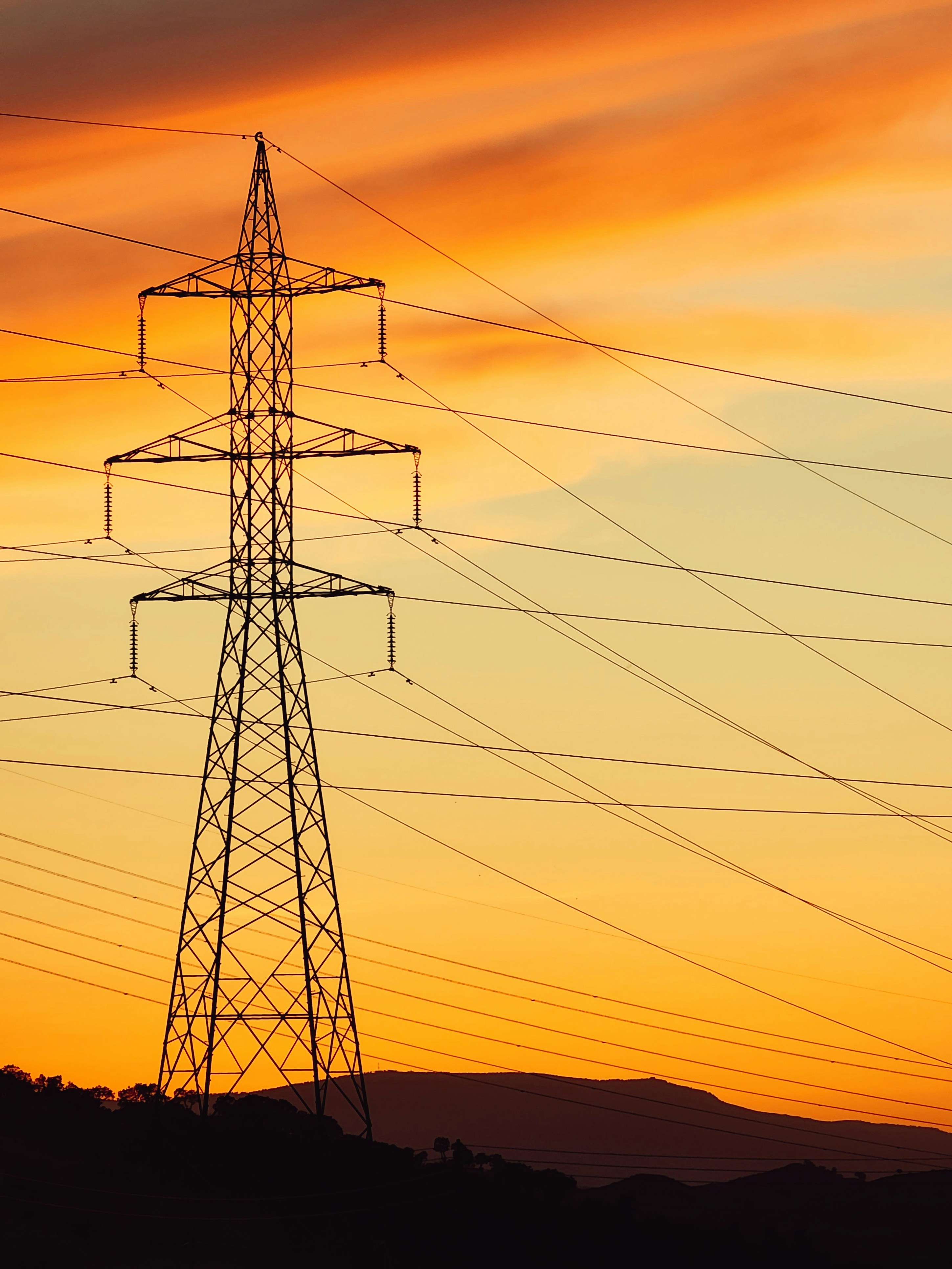 a tall tower with lots of power lines in front of a sunset
