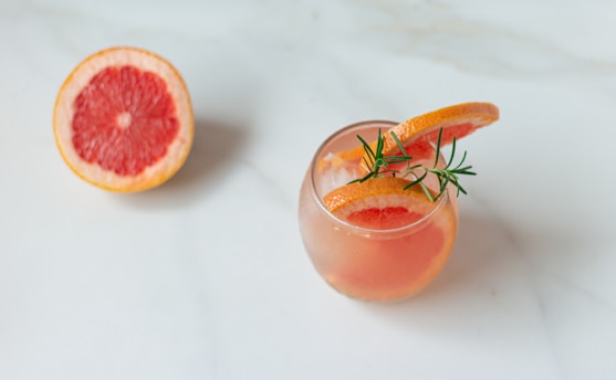 a grapefruit cocktail garnished with a sprig of rosemary