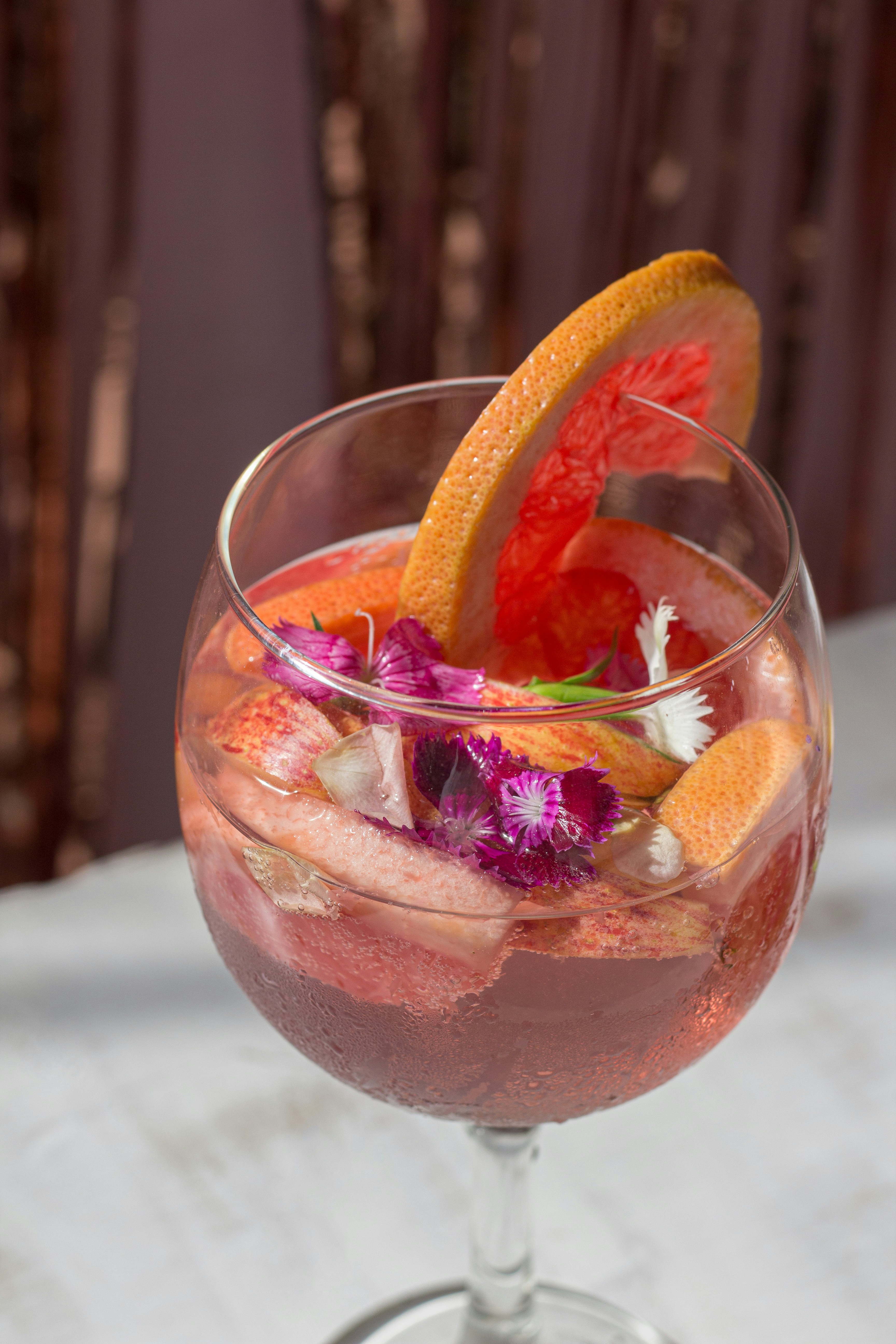 una copa de vino llena de una bebida y adornada con flores