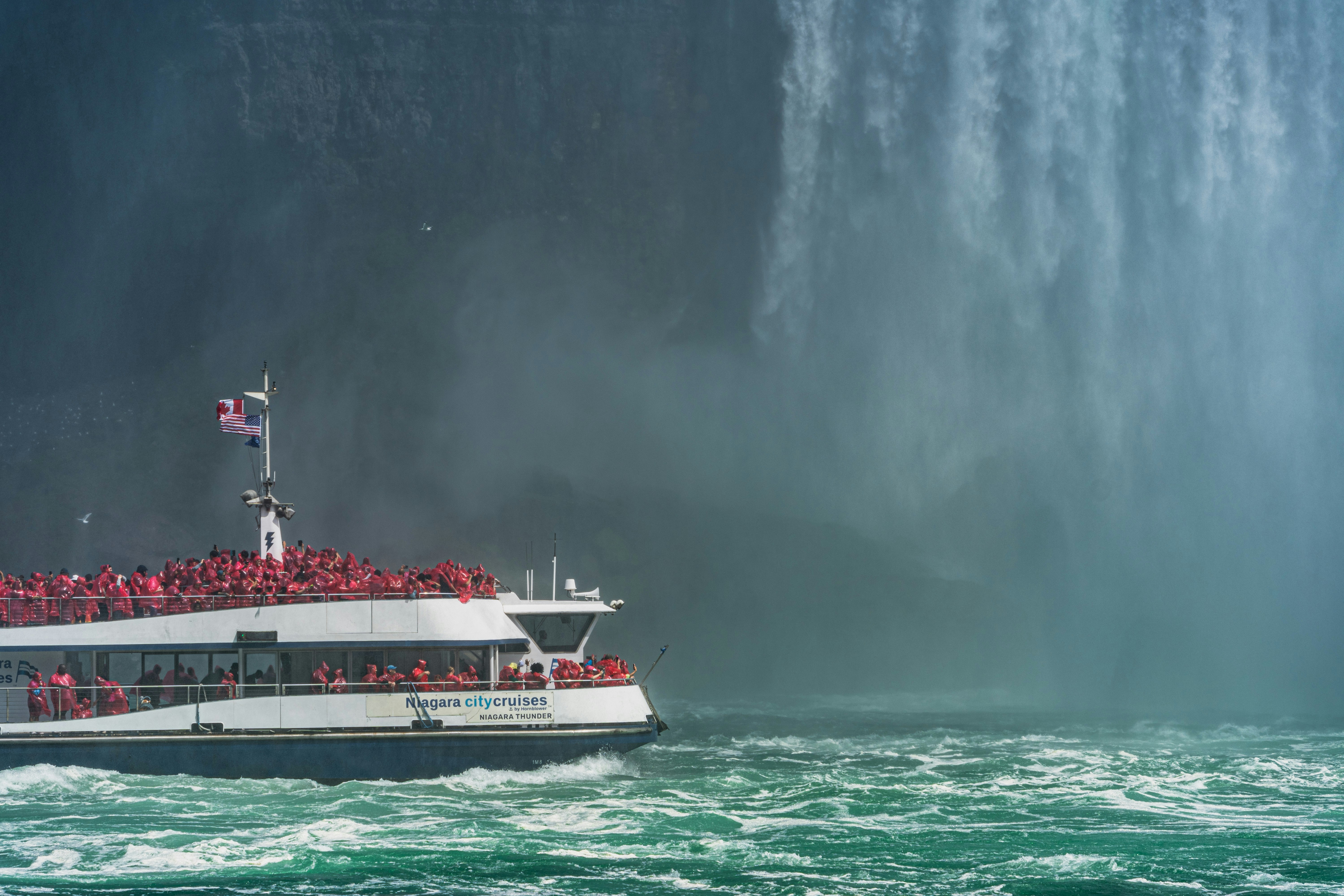 a boat full of people in front of a waterfall