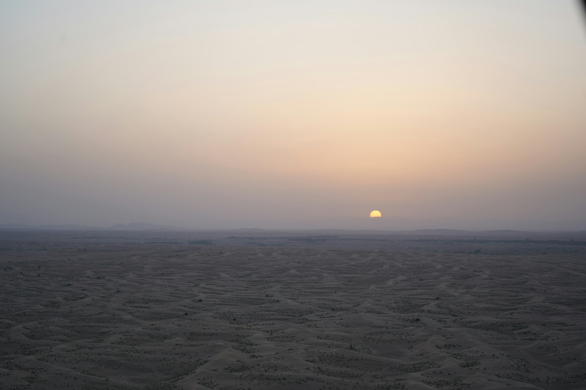 the sun is setting over a sandy beach