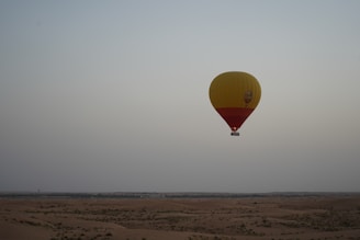 a yellow and red hot air balloon flying in the sky