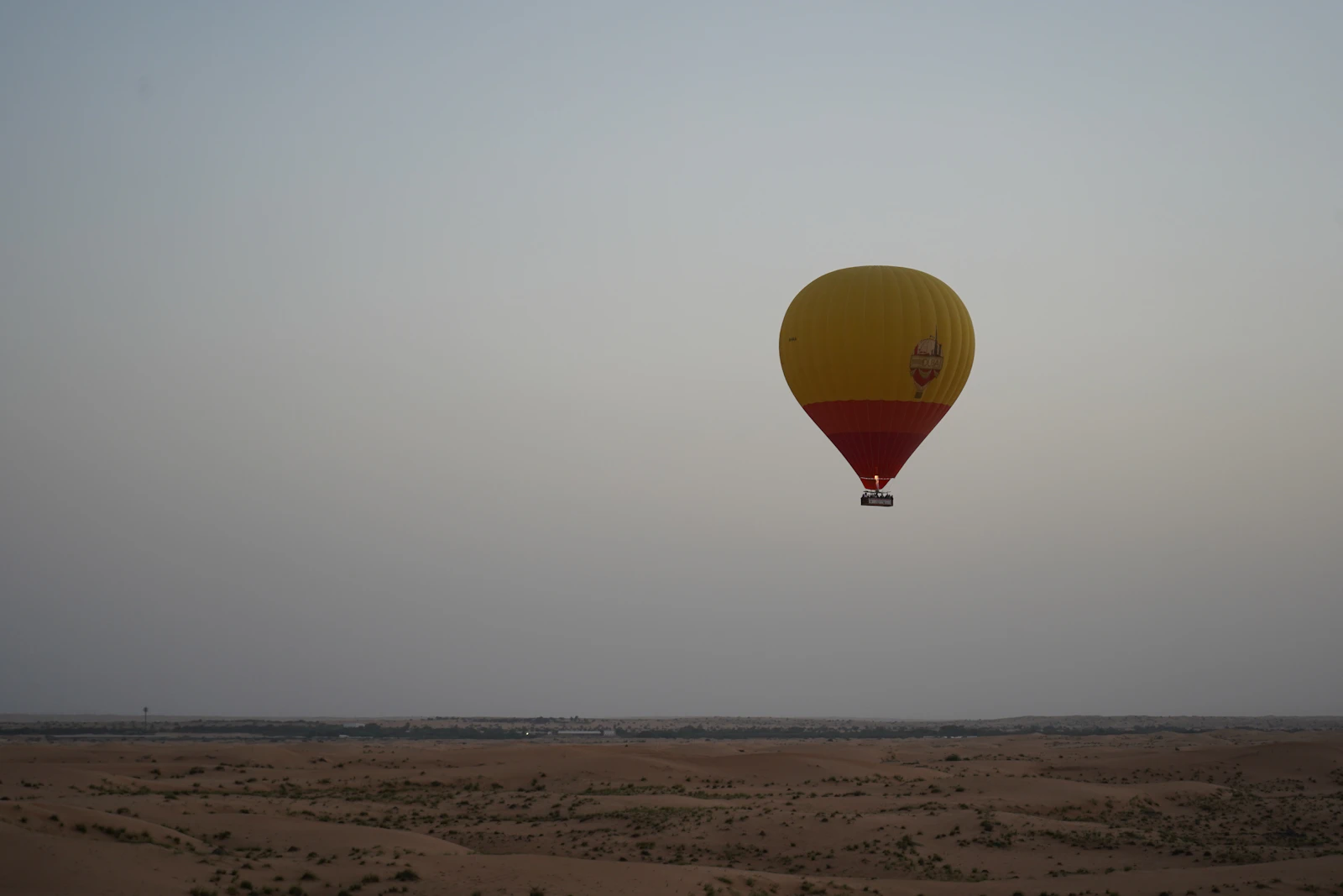Yellow and red hot air balloon above the Dubai desert at dawn