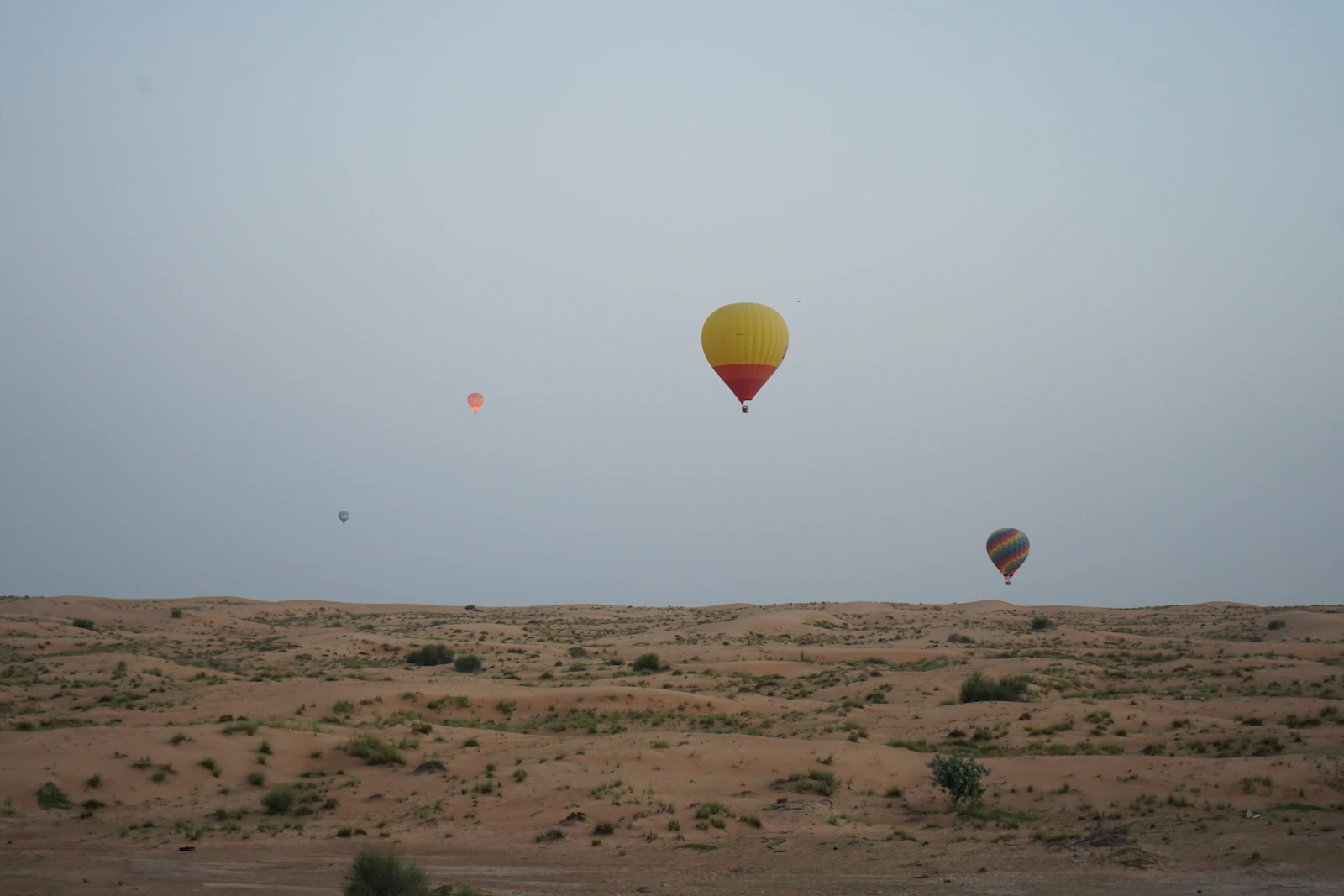 Several hot air balloons drifting over the Dubai desert at sunrise