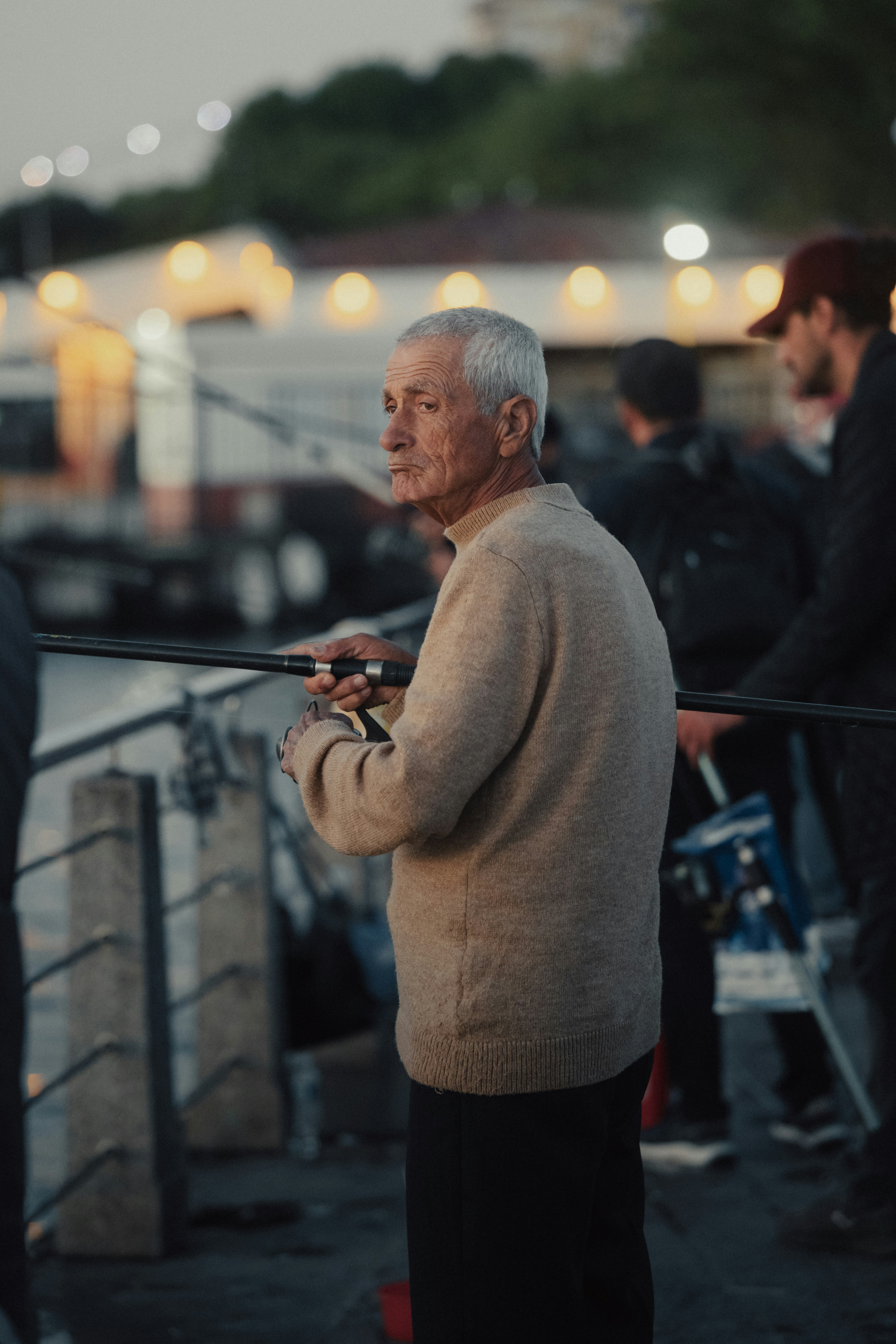 a man holding a fishing pole while standing on a pier