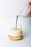 a person pouring a green liquid into a glass