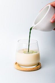 a person pouring a green liquid into a glass
