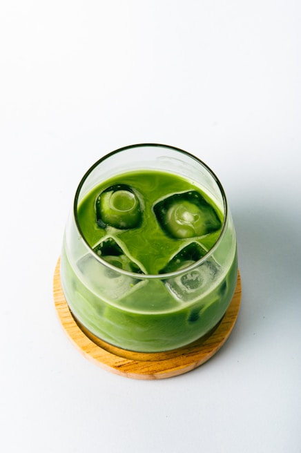 a green drink with ice cubes in it