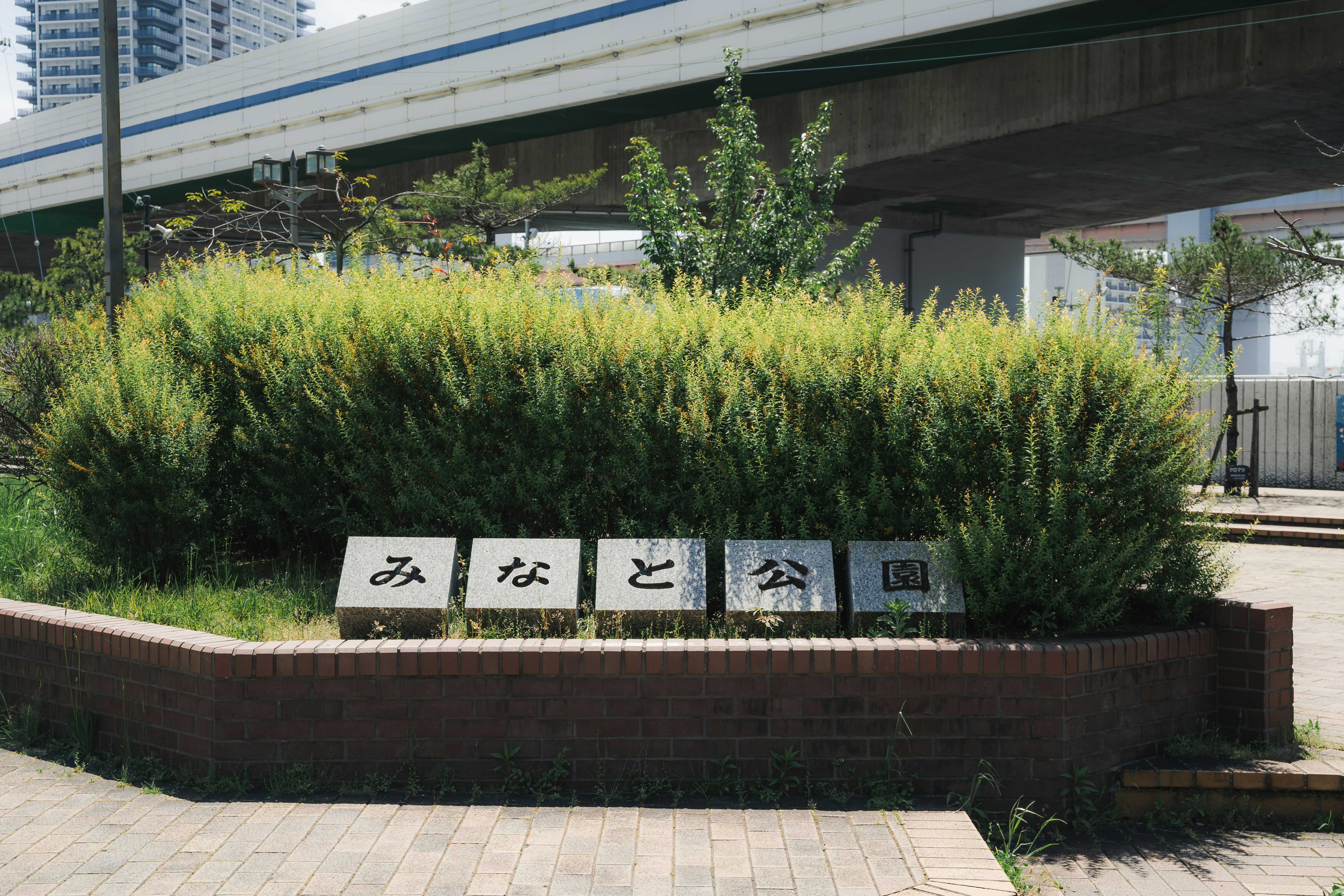 a sign on a brick planter in front of a bridge