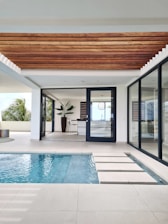 a swimming pool with a wooden ceiling and sliding glass doors