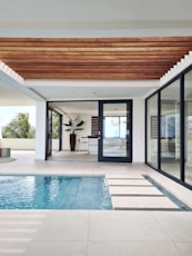 a swimming pool with a wooden ceiling and sliding glass doors