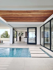 a swimming pool with a wooden ceiling and sliding glass doors