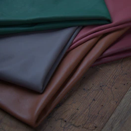 a pile of different colors of leather on a wooden floor